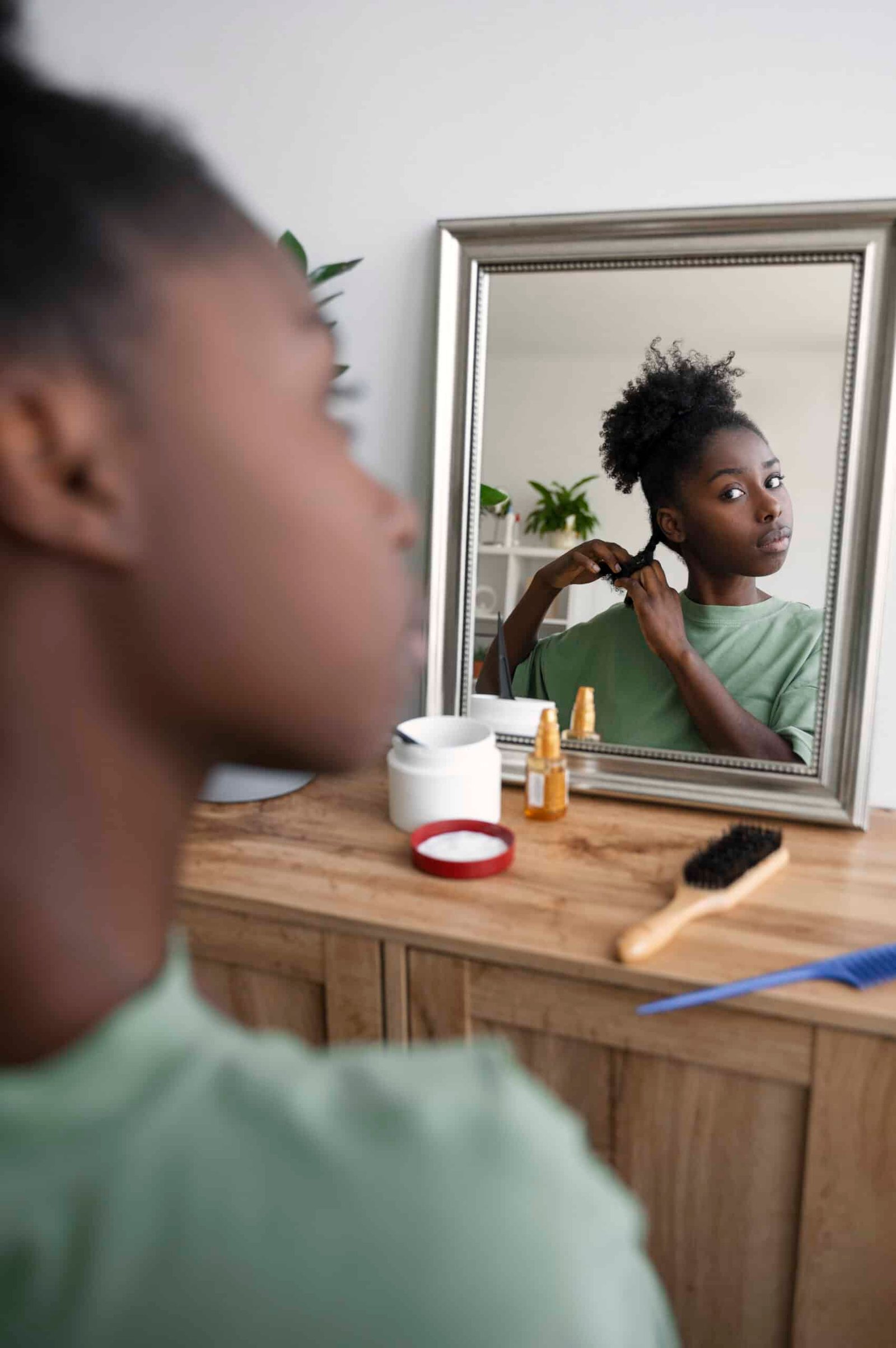 Mujer racializada mirando su pelo en el espejo, diversidad capilar